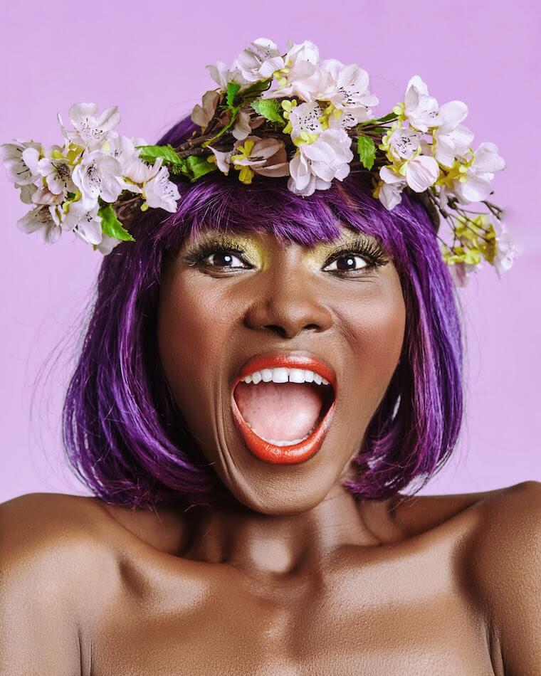 black woman with purple hair wearing flower crown