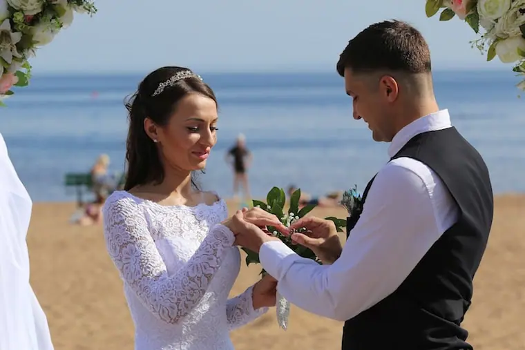 bride and groom exchanging rings on beach wedding