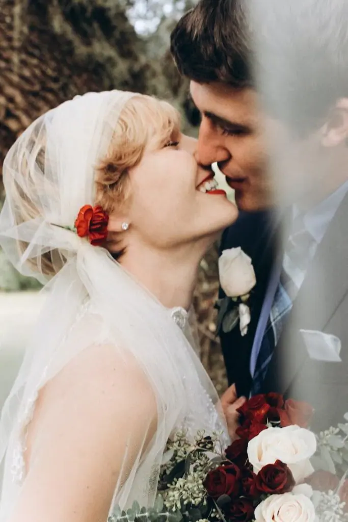 bride and groom with bouqet of red and white roses