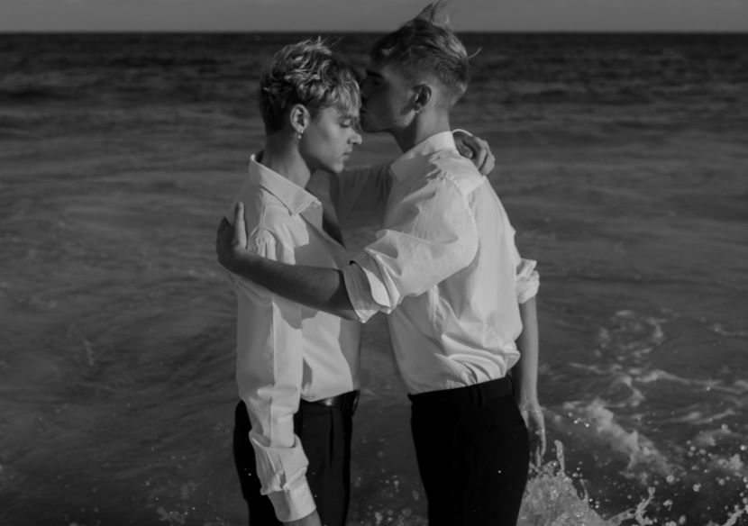 married gay couple standing in the ocean