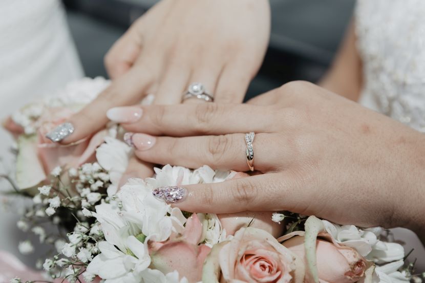 2 brides wearing rings and carrying bouquets