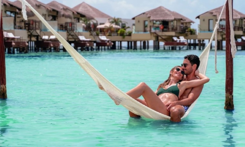 palafitos overwater bungalow couple sitting in hammock in the ocean