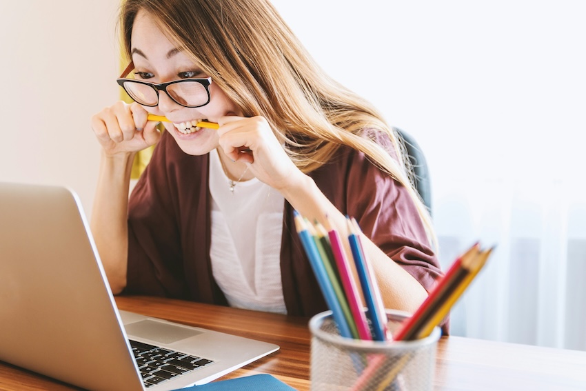 girl biting pencil at desk