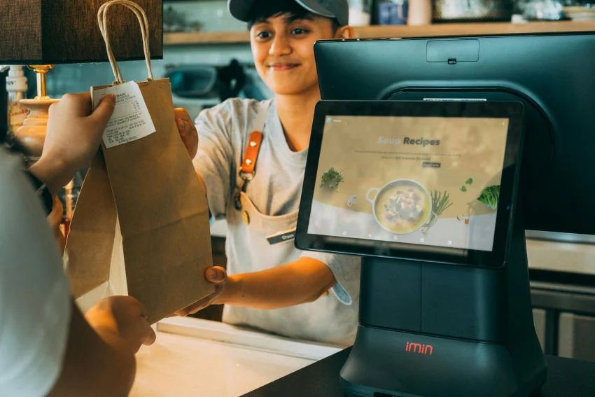 cash counter at a cafe with staff handing over food parcel