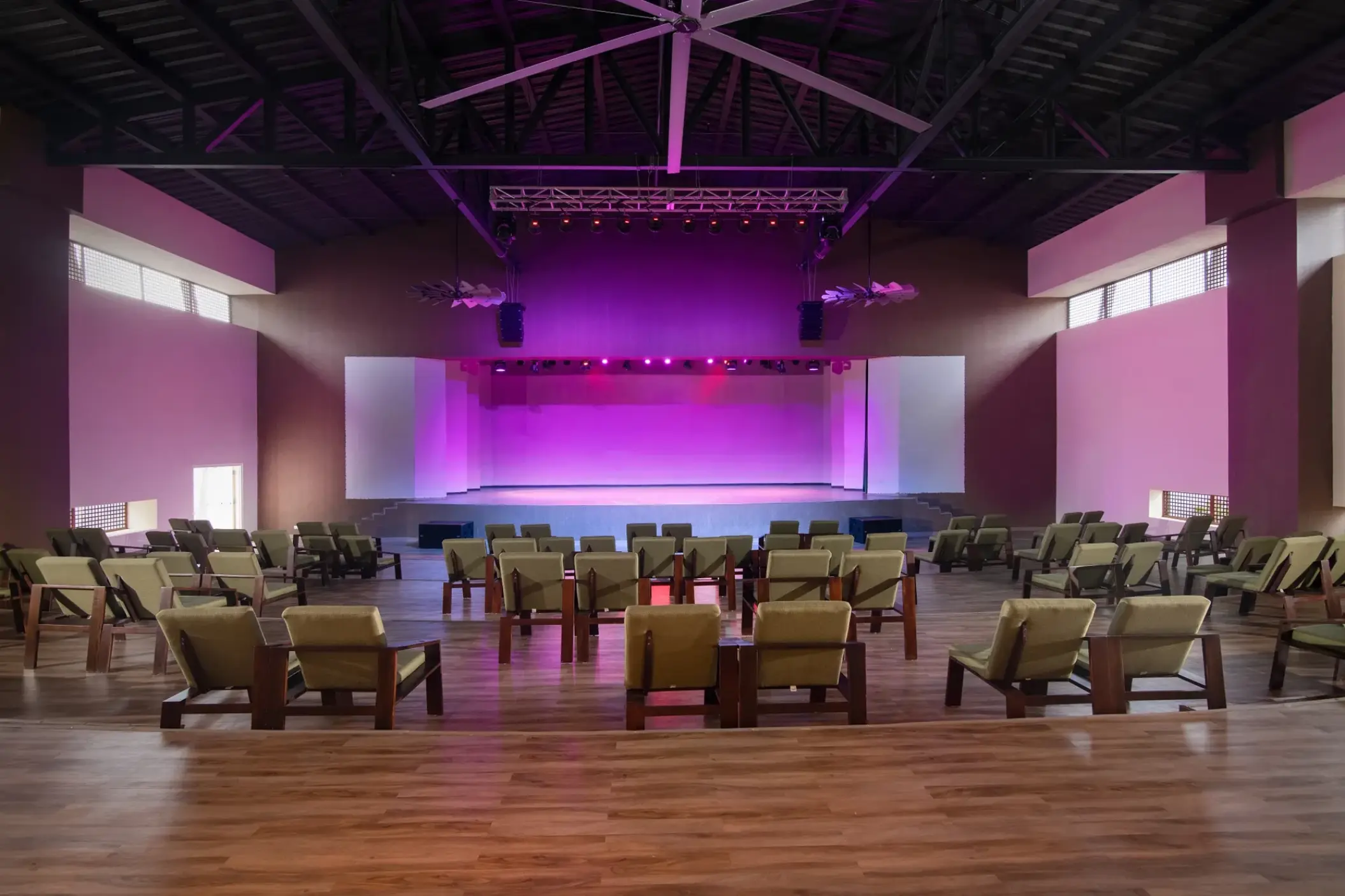 Indoor theater with a purple lit stage and rows of armchairs at Dreams Macao Beach, Punta Cana