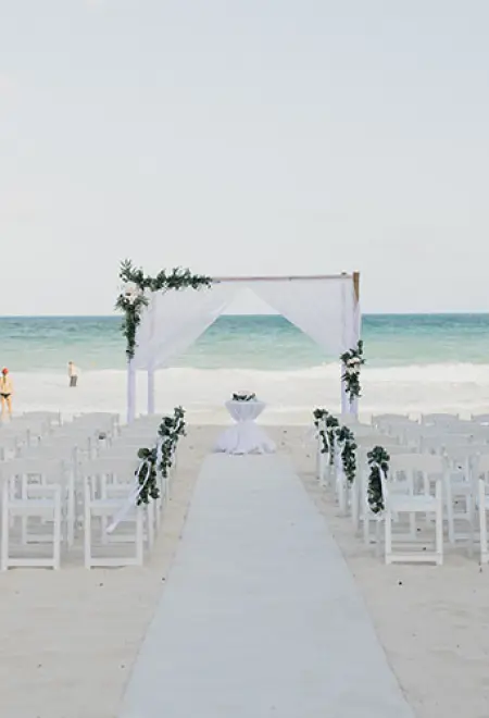 Beachfront wedding ceremony with white aisle and floral arch for Kathryn & Van's wedding