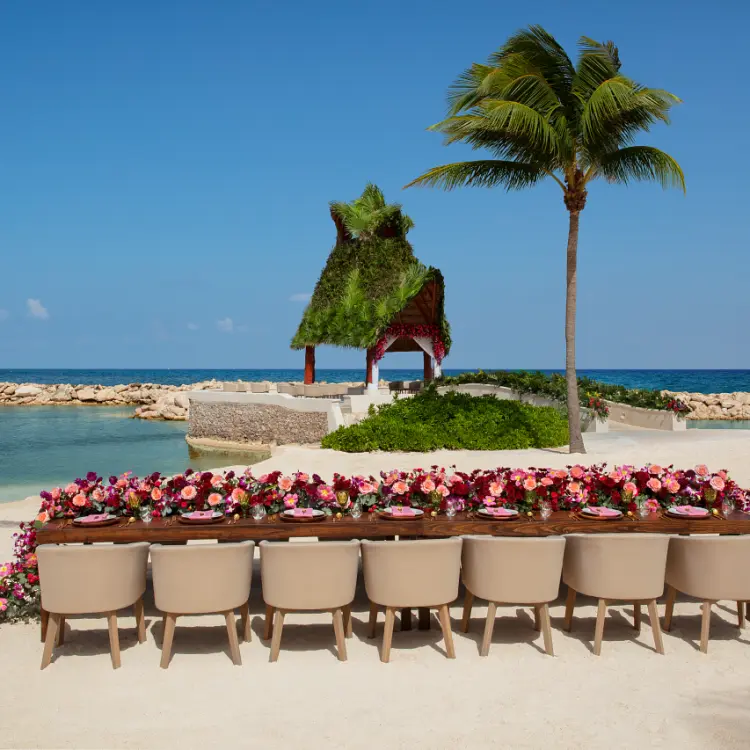 Beachfront wedding reception table with pink floral runner at Dreams Aventuras, Riviera Maya