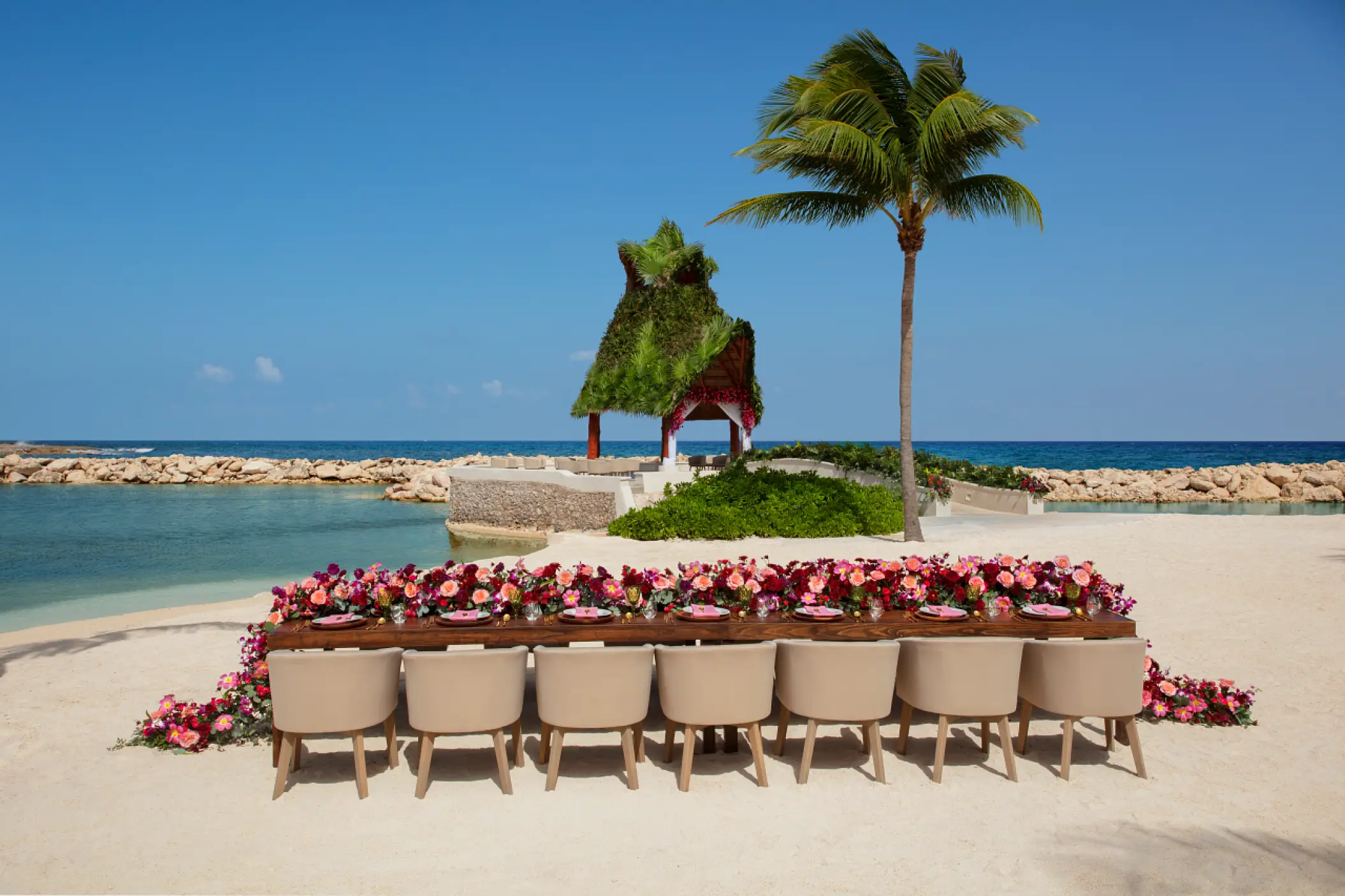 Beachfront wedding reception table with pink floral runner at Dreams Aventuras, Riviera Maya