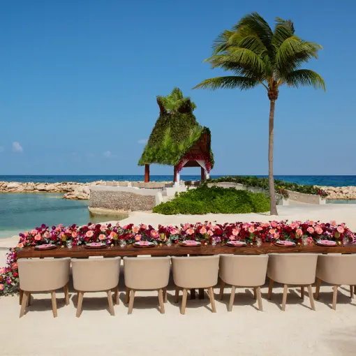 Beachfront wedding reception table with pink floral runner at Dreams Aventuras, Riviera Maya