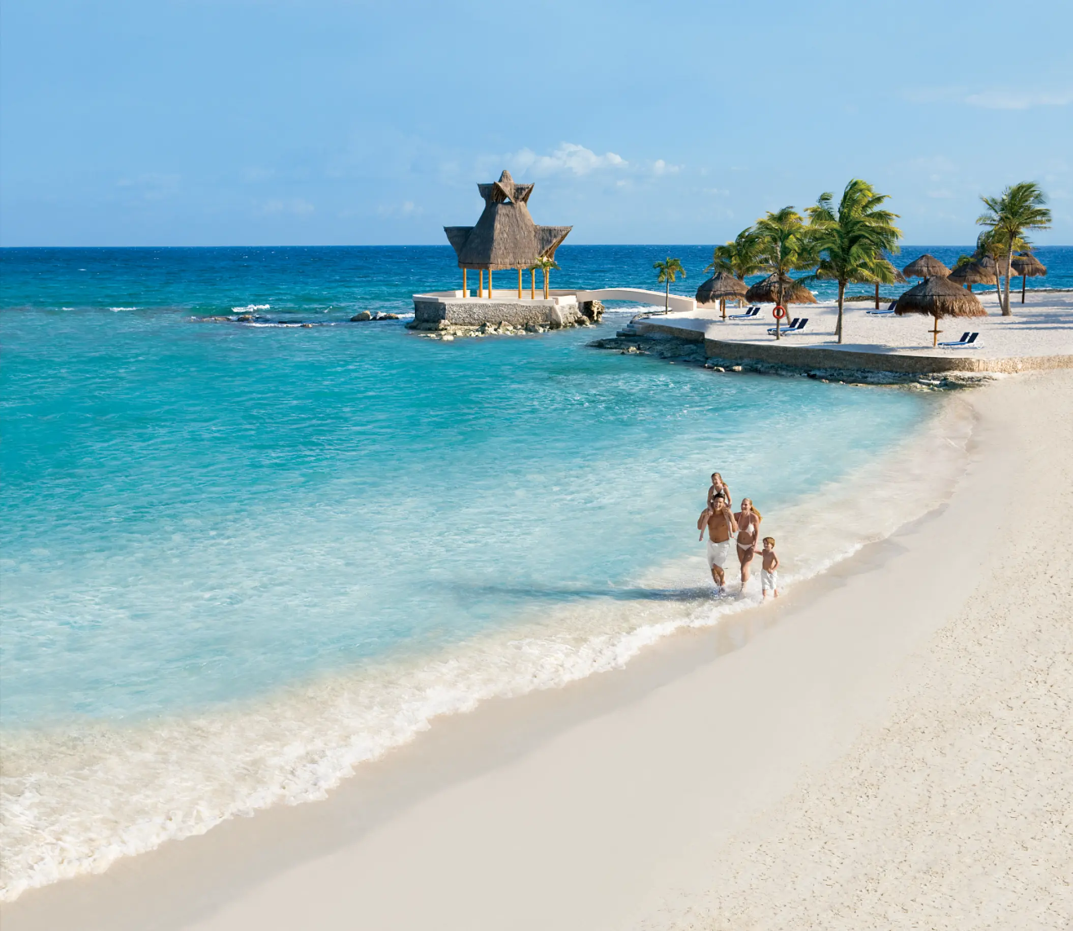 Family walking along the turquoise shoreline at Dreams Aventuras, Riviera Maya