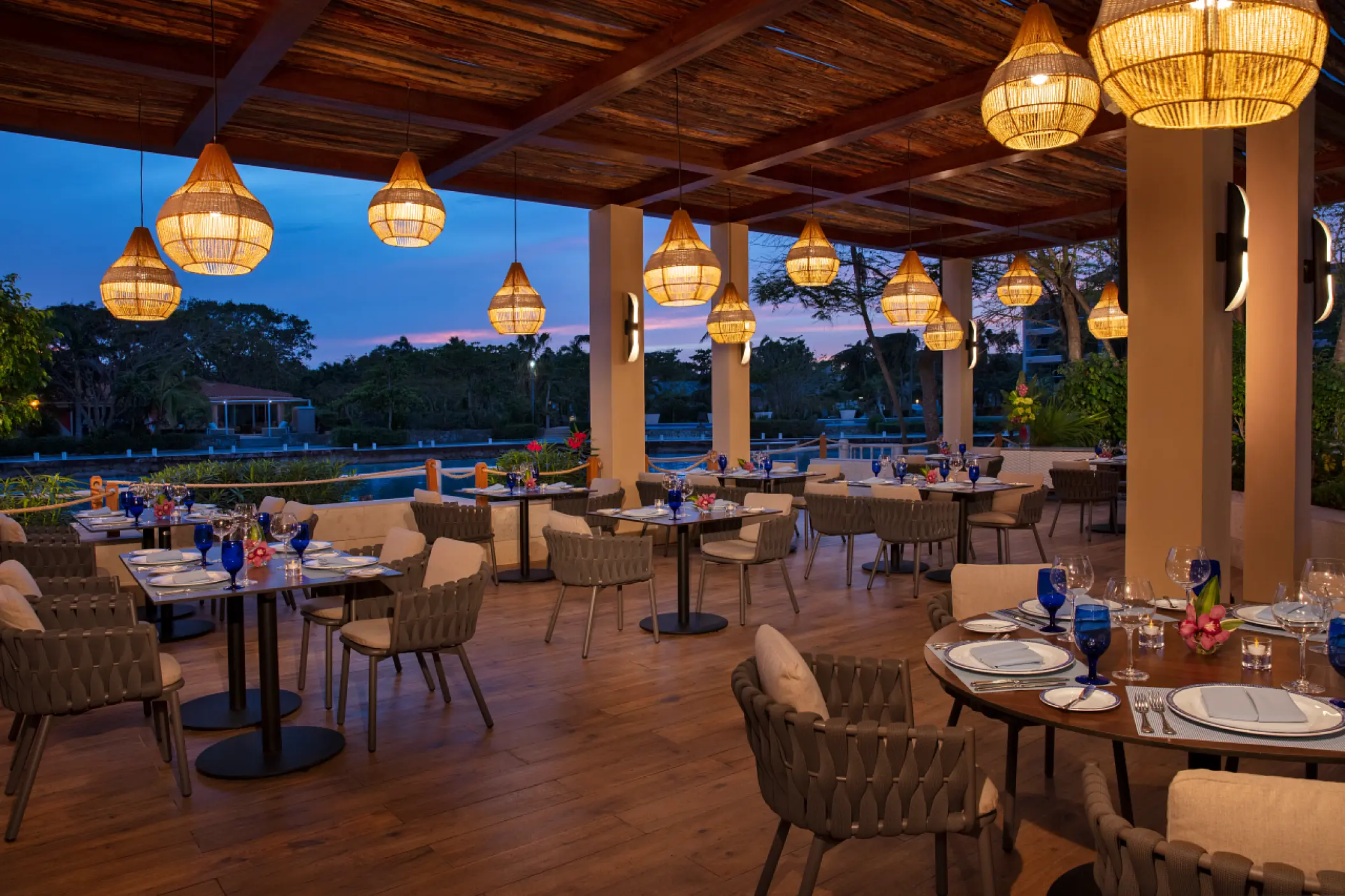 Outdoor terrace restaurant with wicker pendant lights at Dreams Aventuras, Riviera Maya