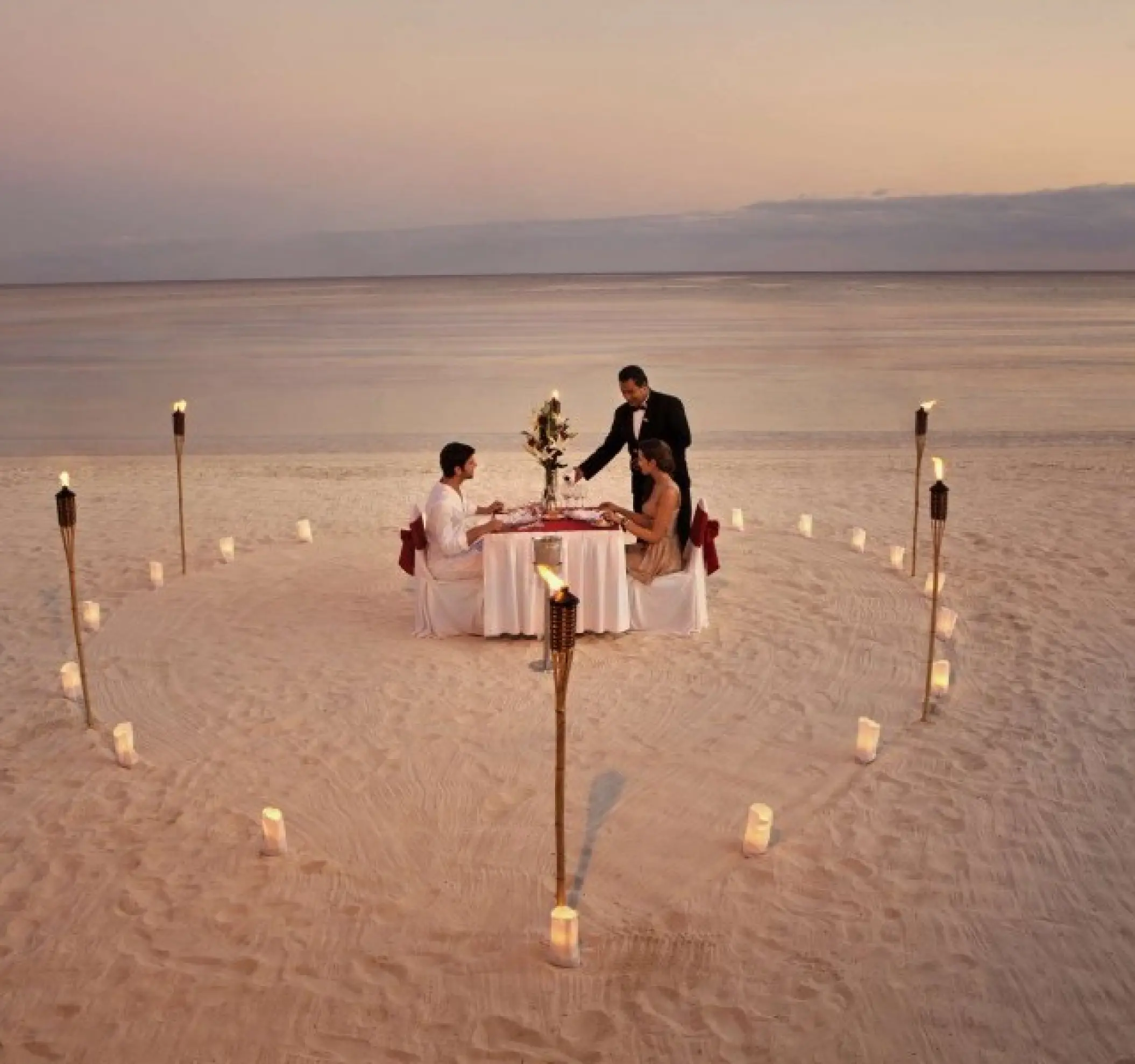 Private beach dinner with tiki torches and candles for a couple at Barcelo Maya Beach, Riviera Maya