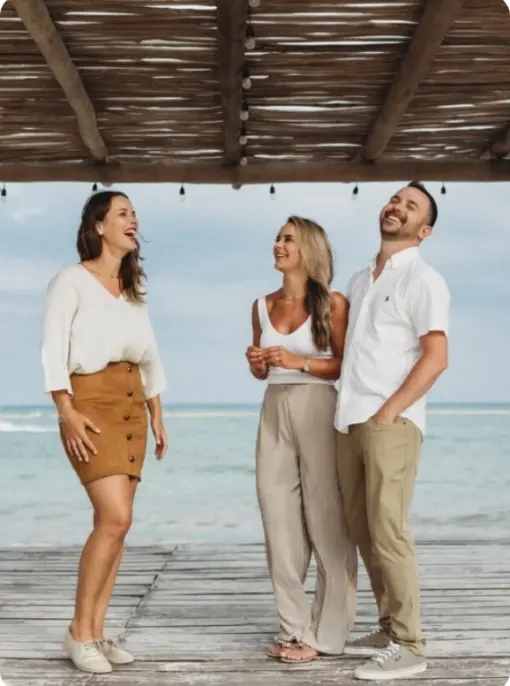 Paradise Weddings team members laughing on a beach pier under a wooden pergola