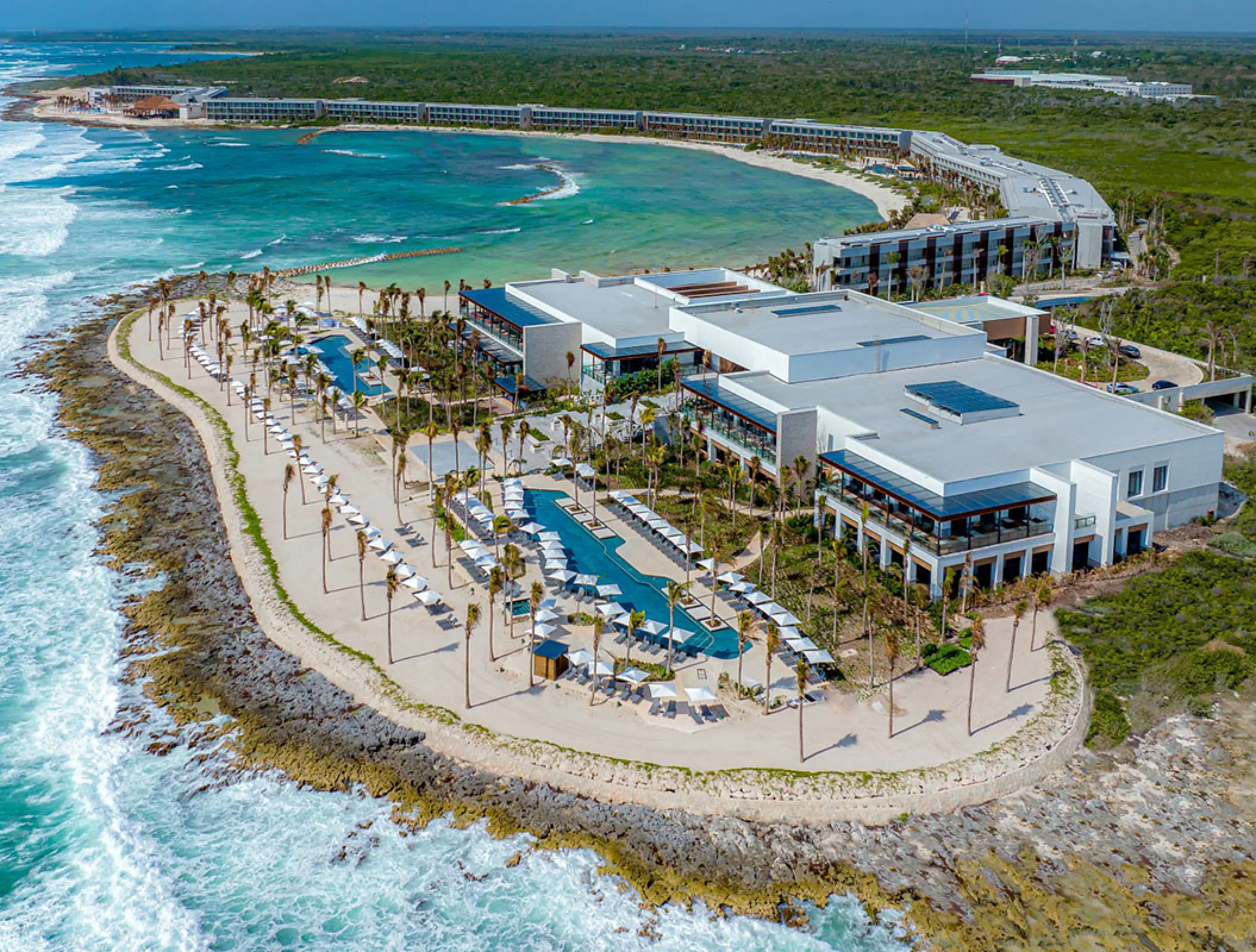 Aerial view of Hilton Tulum beachfront buildings and pools overlooking the bay, Tulum