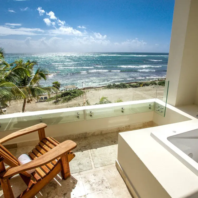 Ocean view balcony with a whirlpool tub and wooden chair at Akumal Bay Beach & Wellness, Riviera Maya