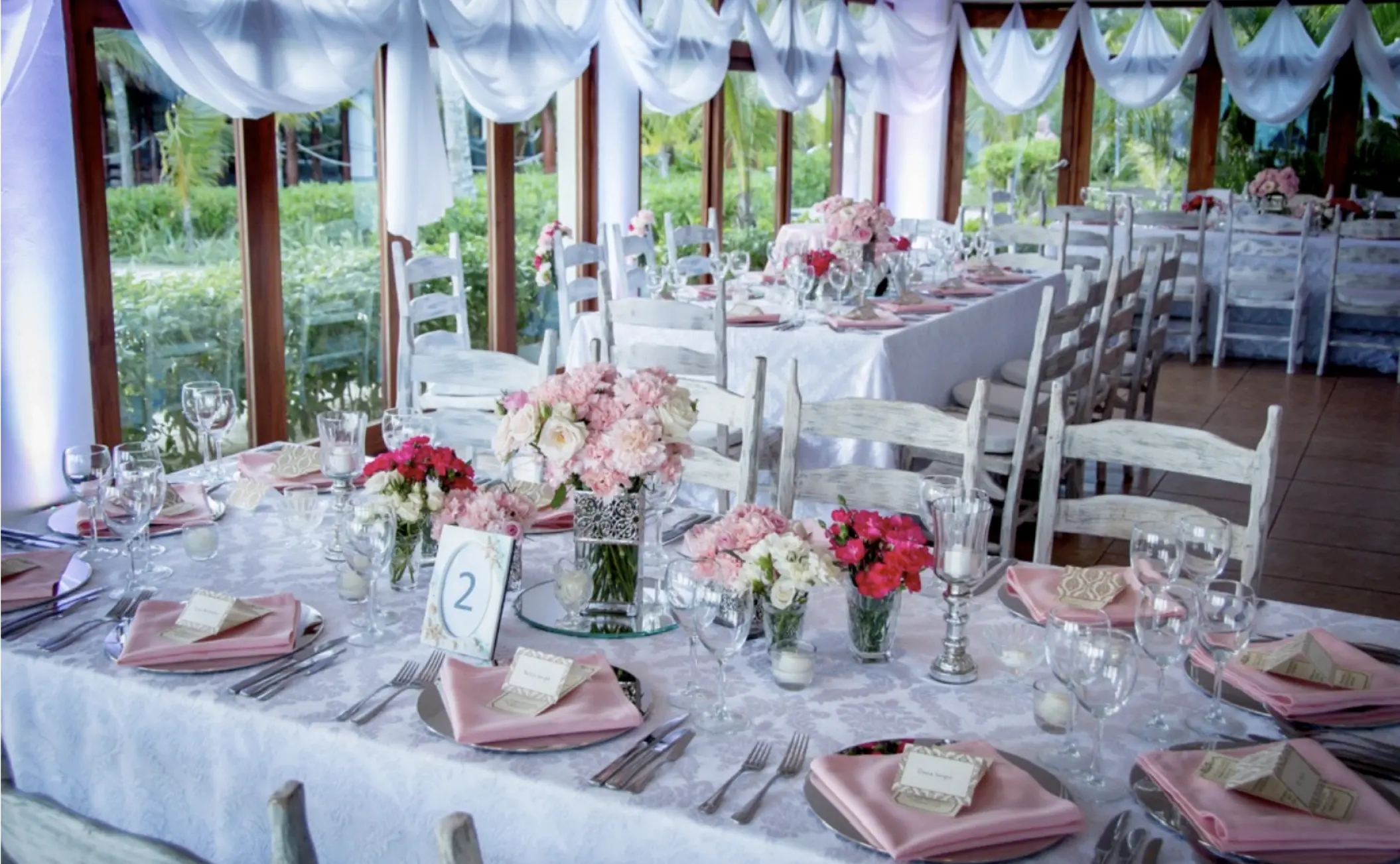 Indoor wedding reception setup with pink floral centerpieces at Akumal Bay Beach & Wellness Resort, Riviera Maya