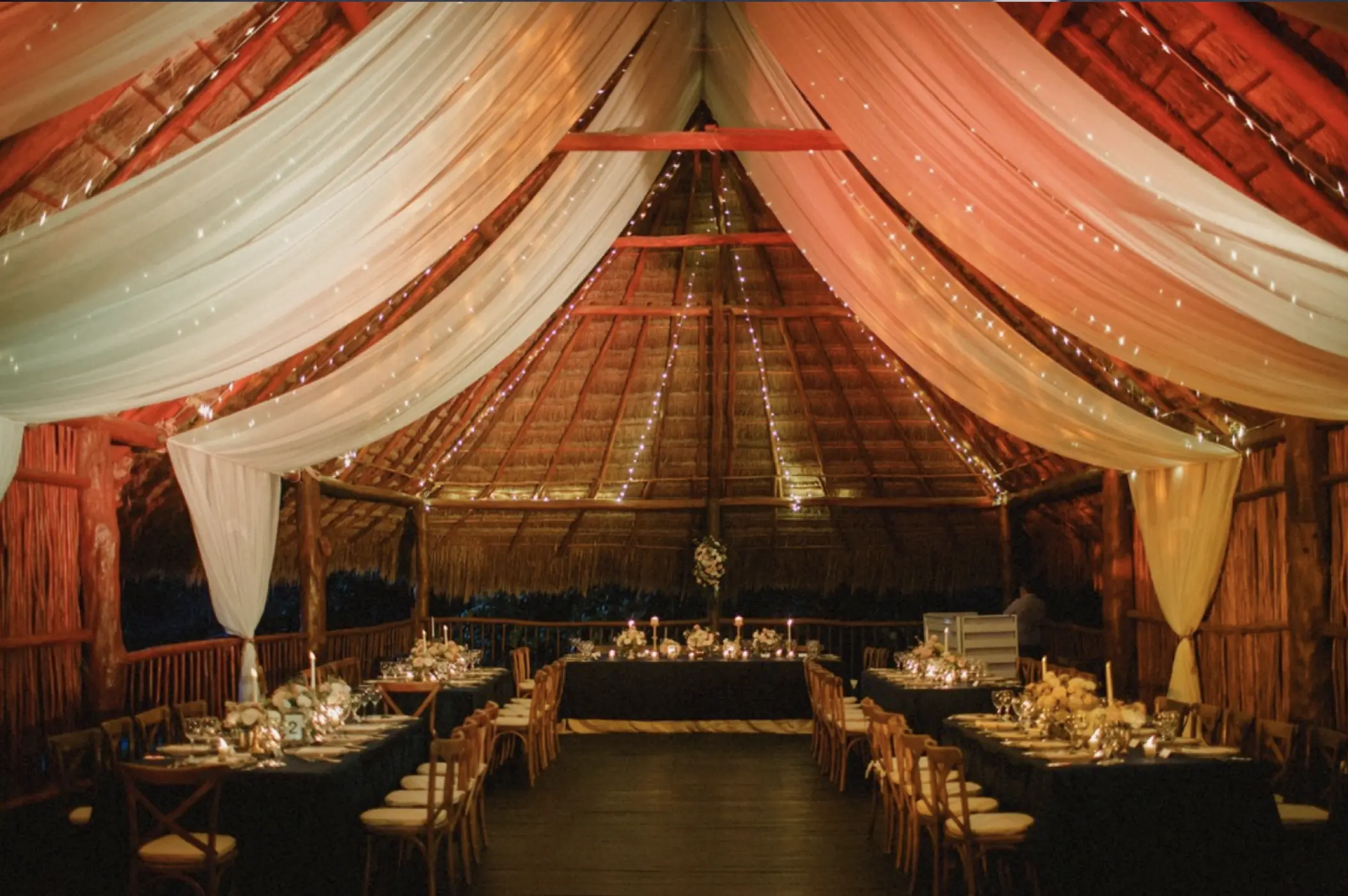 Wedding reception under a draped palapa with string lights at Akumal Bay Beach & Wellness Resort, Riviera Maya