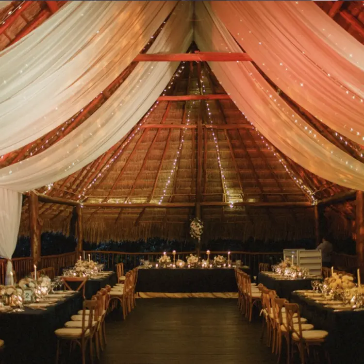 Wedding reception under a draped palapa with string lights at Akumal Bay Beach & Wellness Resort, Riviera Maya