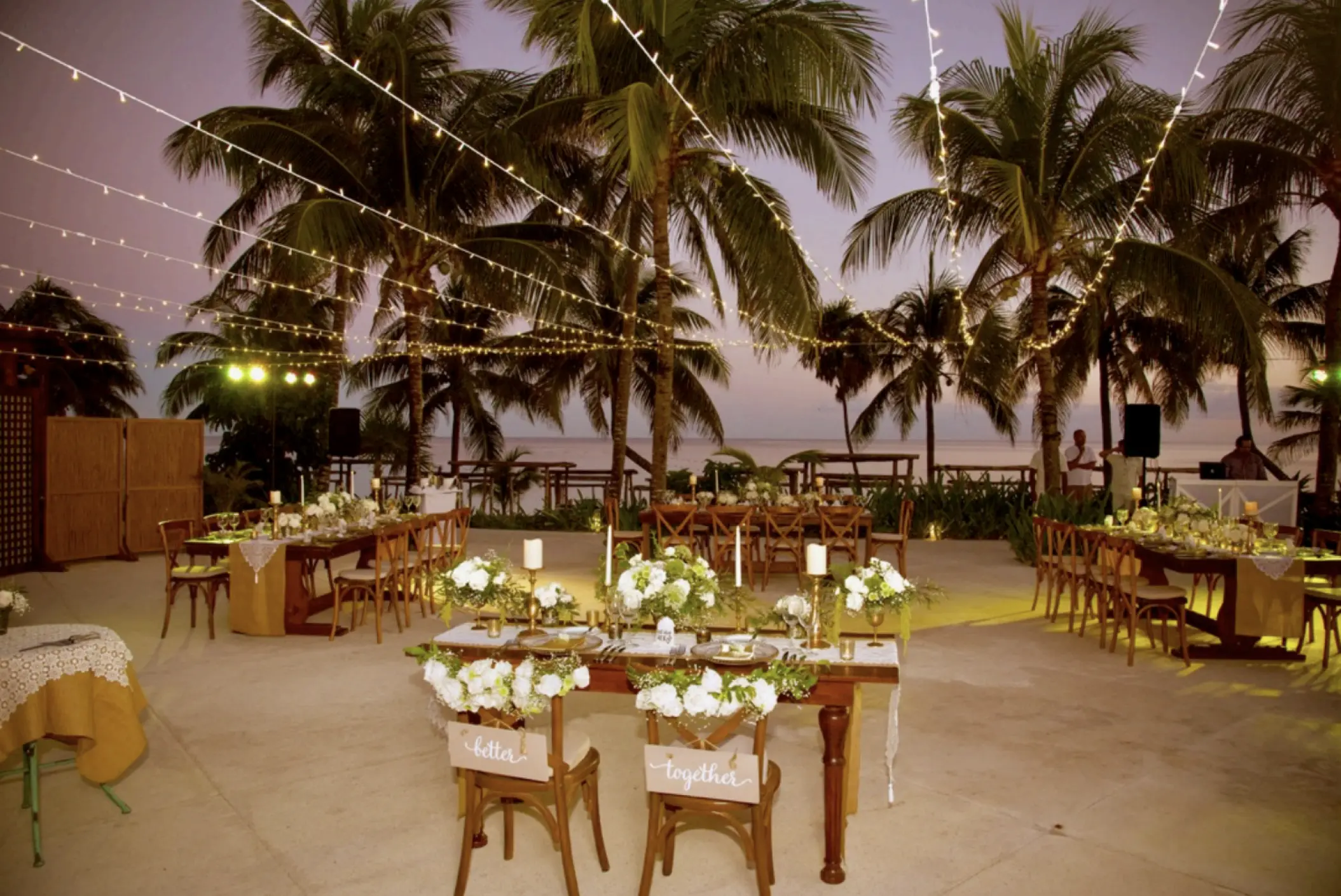 Outdoor wedding reception setup with string lights and palm trees at Akumal Bay Beach Resort, Riviera Maya
