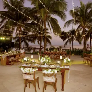 Outdoor wedding reception setup with string lights and palm trees at Akumal Bay Beach Resort, Riviera Maya