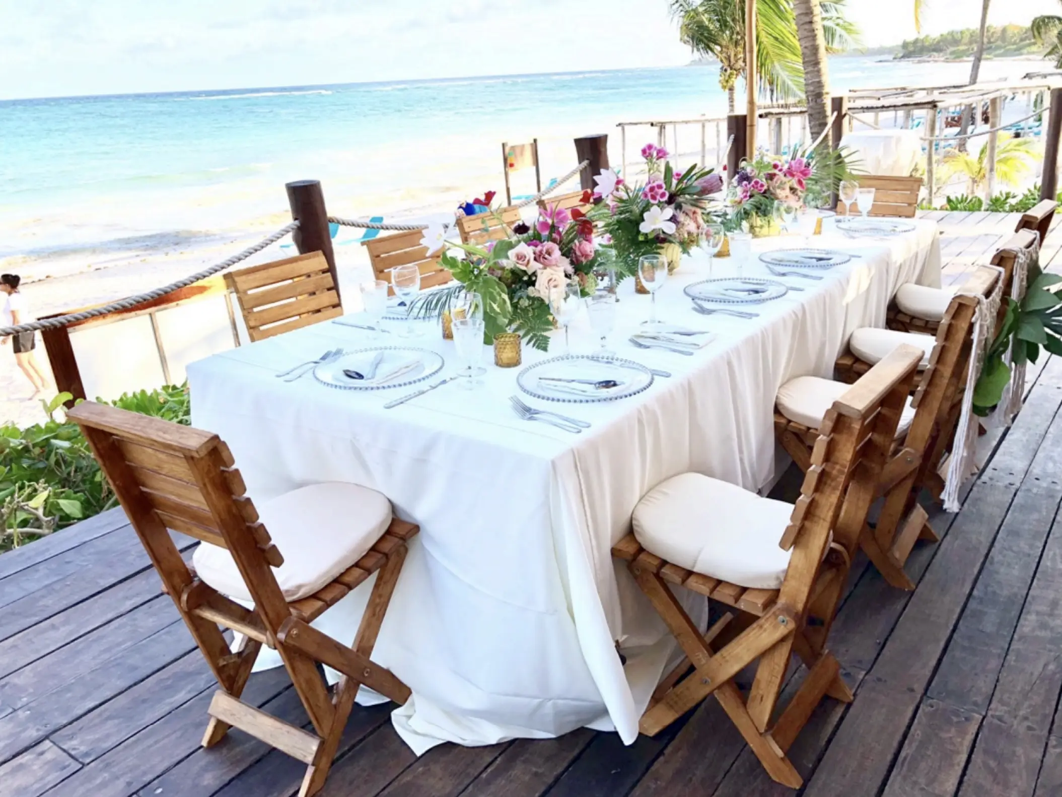 Long wedding reception table on a wooden deck at Akumal Bay Beach & Wellness Resort, Riviera Maya
