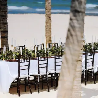 Beachfront wedding reception table with greenery and white candles at Allegro Playacar, Playa Del Carmen