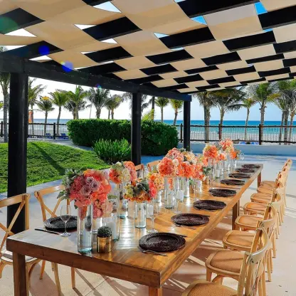 Wedding reception table with orange floral centerpieces under a terrace pergola at Allegro Playacar, Playa Del Carmen