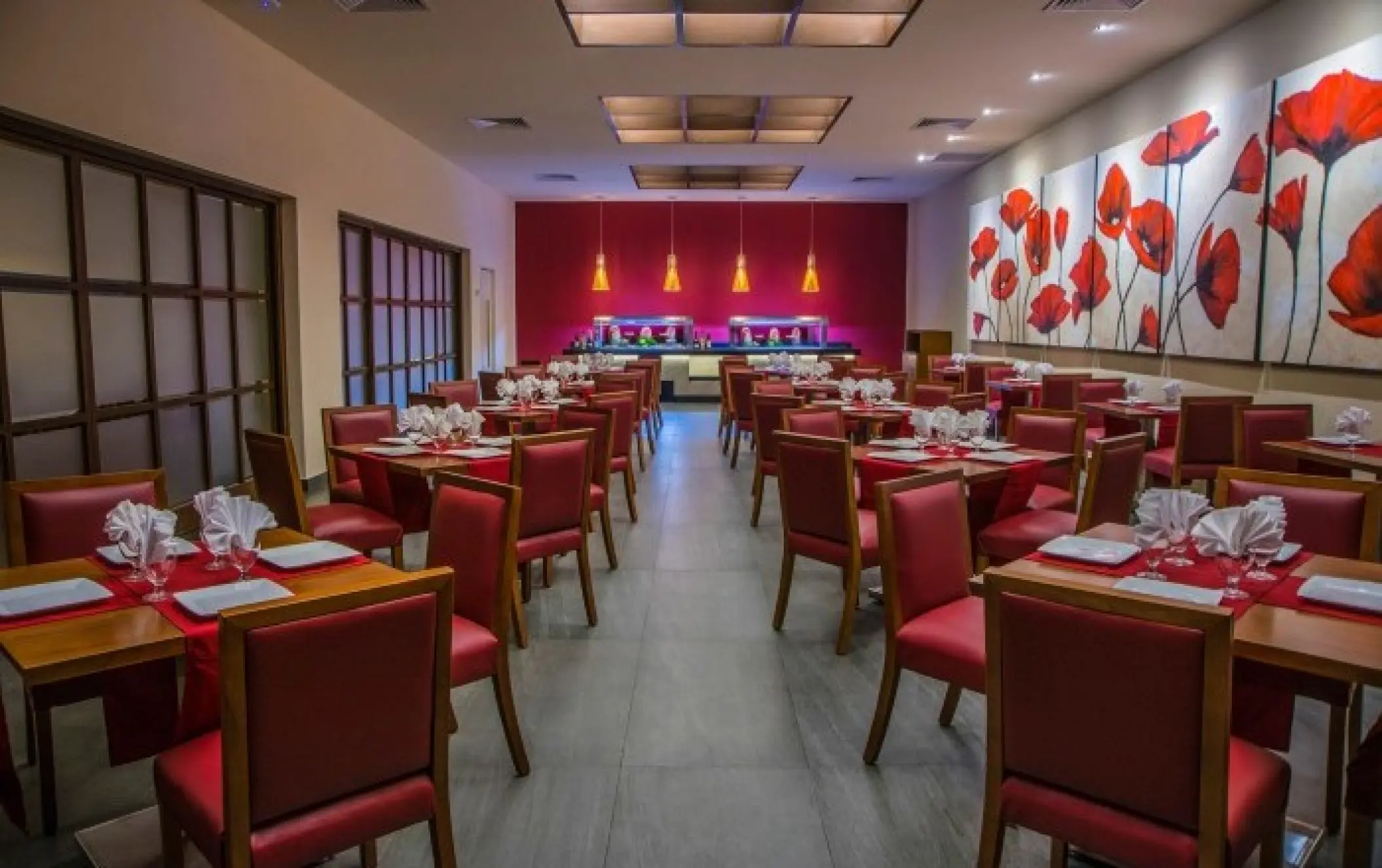 Indoor wedding reception venue with red chairs and floral wall art at Allegro Playacar, Playa Del Carmen
