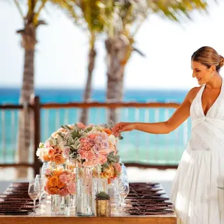 Bride touching flower centerpieces at a reception table at Allegro Playacar, Playa Del Carmen