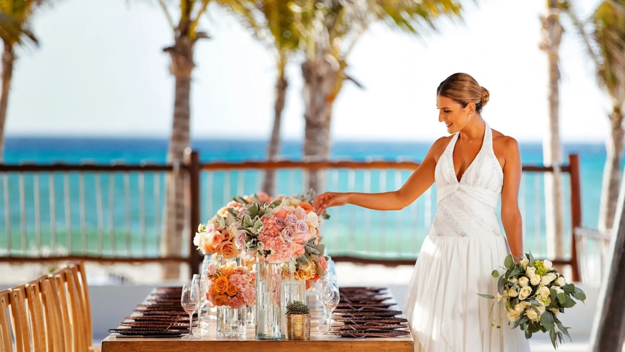 Bride touching flower centerpieces at a reception table at Allegro Playacar, Playa Del Carmen