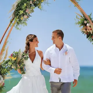 Bride and groom walking under a floral circular arch at Allegro Playacar, Playa Del Carmen