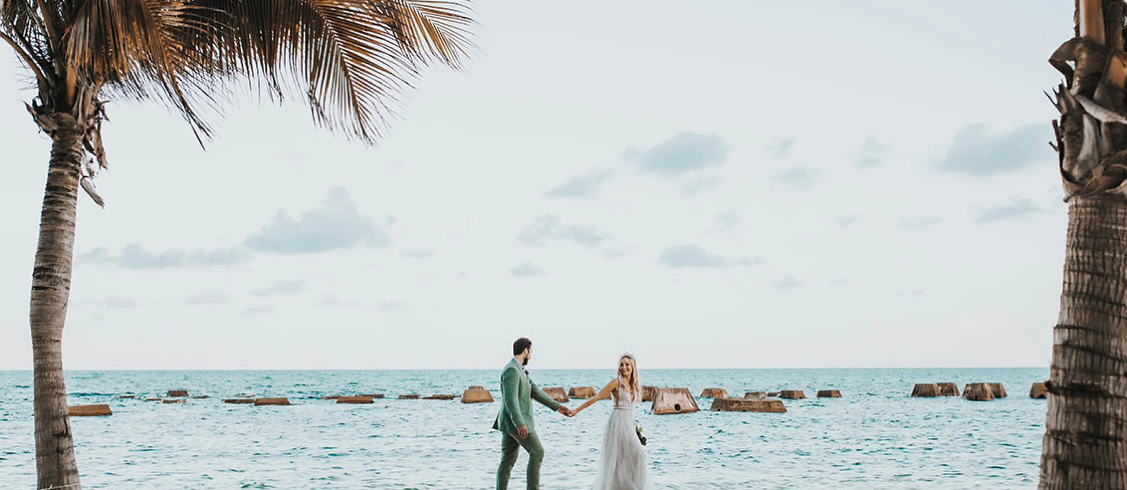 Wide shot of newlyweds walking on the beach