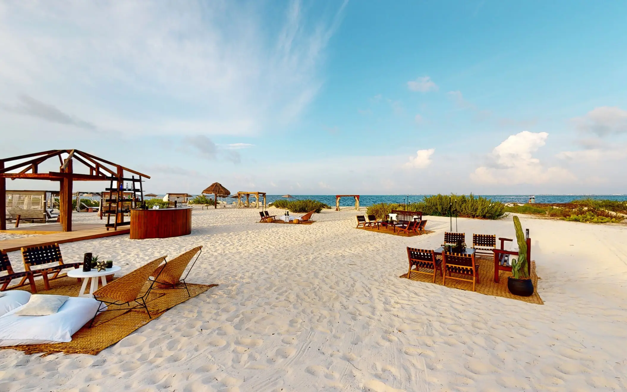 Outdoor beach venue with wooden seating and lounge furniture at Atelier Playa Mujeres, Cancun