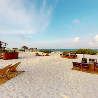 Outdoor beach venue with wooden seating and lounge furniture at Atelier Playa Mujeres, Cancun