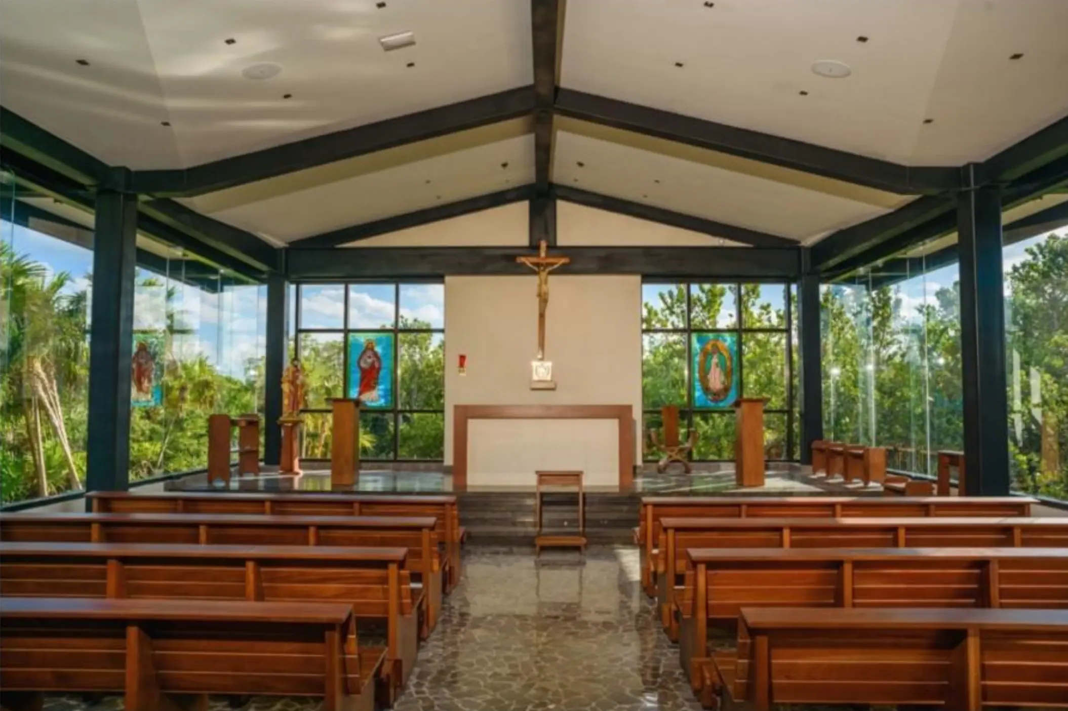 Modern wedding chapel with glass walls and wooden pews at Atelier Playa Mujeres, Cancun