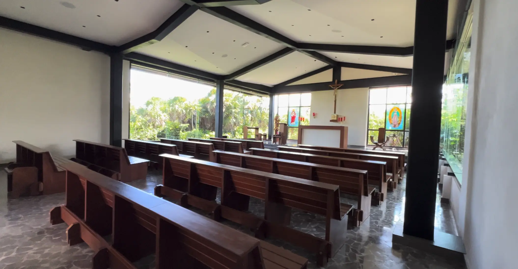 Modern wedding chapel with dark wood pews and floor-to-ceiling windows at Atelier Playa Mujeres, Cancun
