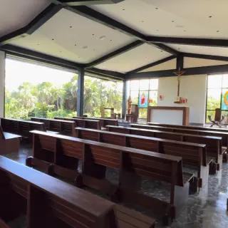 Modern wedding chapel with dark wood pews and floor-to-ceiling windows at Atelier Playa Mujeres, Cancun