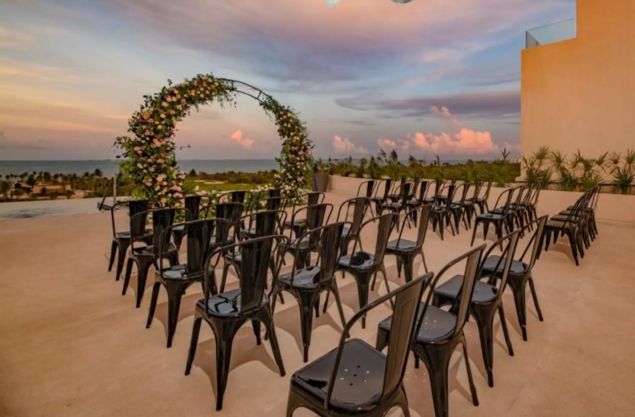 Rooftop wedding ceremony setup with black chairs and floral arch at Atelier Playa Mujeres, Cancun