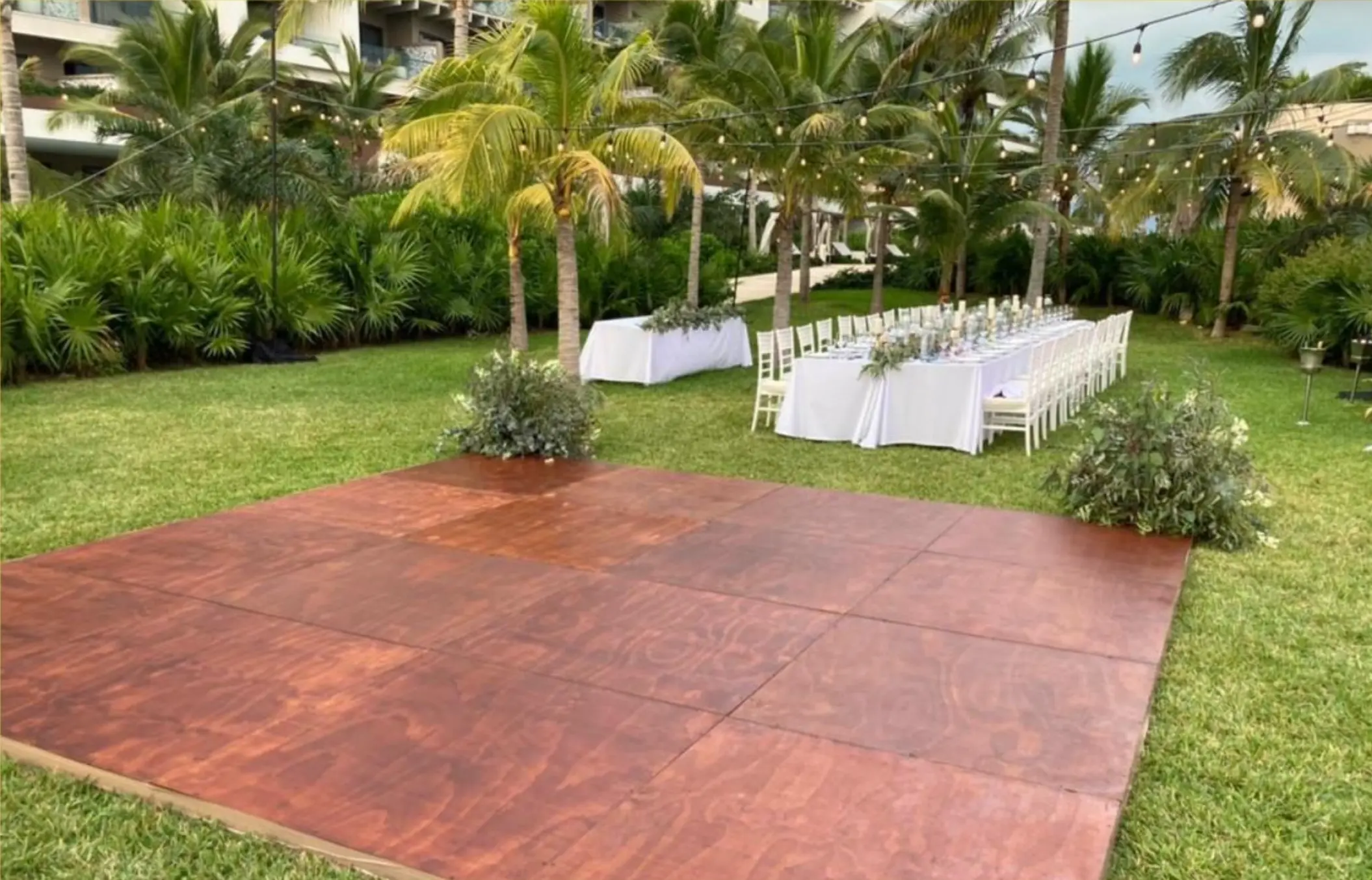 Wooden dance floor and wedding reception table on the garden lawn at Atelier Playa Mujeres, Cancun