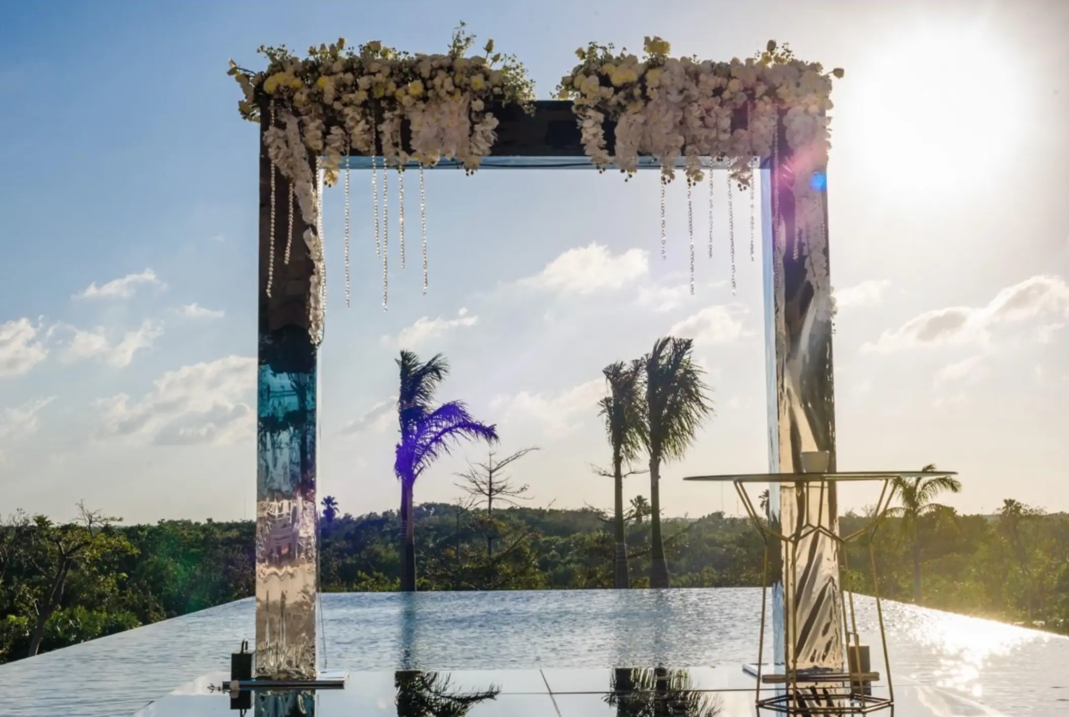 Mirrored wedding ceremony arch overlooking an infinity pool at Atelier Playa Mujeres, Cancun