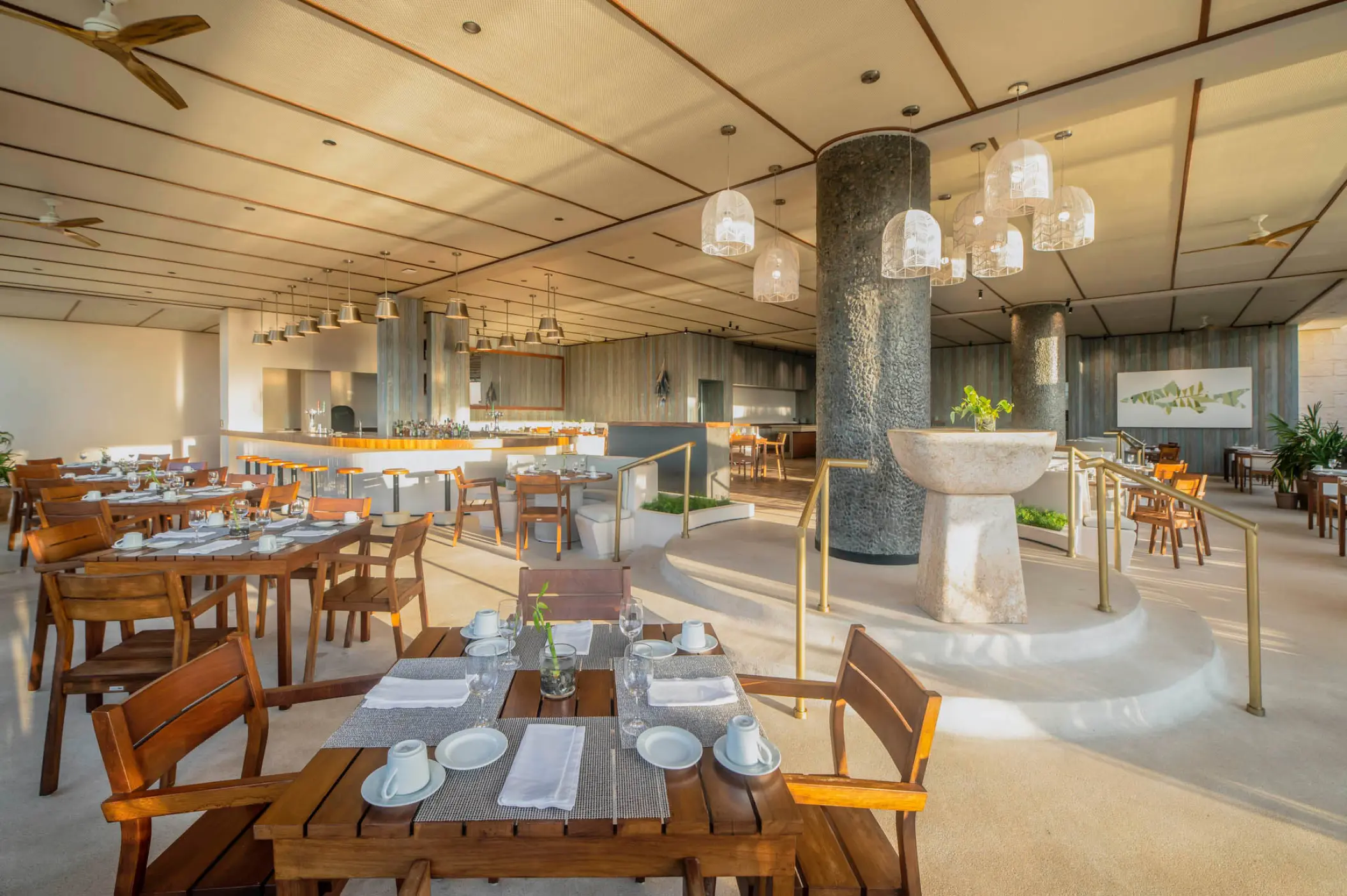 El Suspiro restaurant dining area with wooden tables and decorative stone fountain at Atelier Playa Mujeres, Cancun
