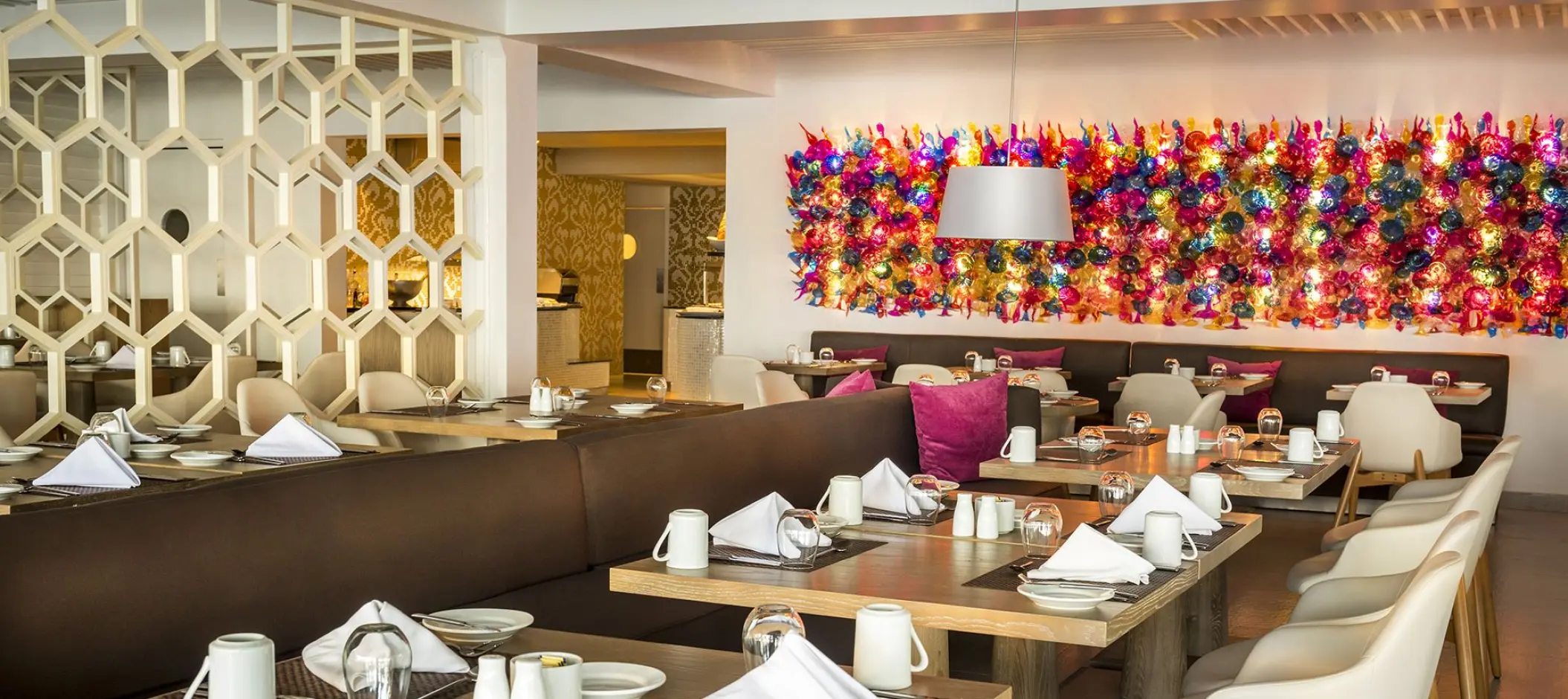 Modern restaurant dining room with a colorful mosaic wall at Azul Beach Resort Negril