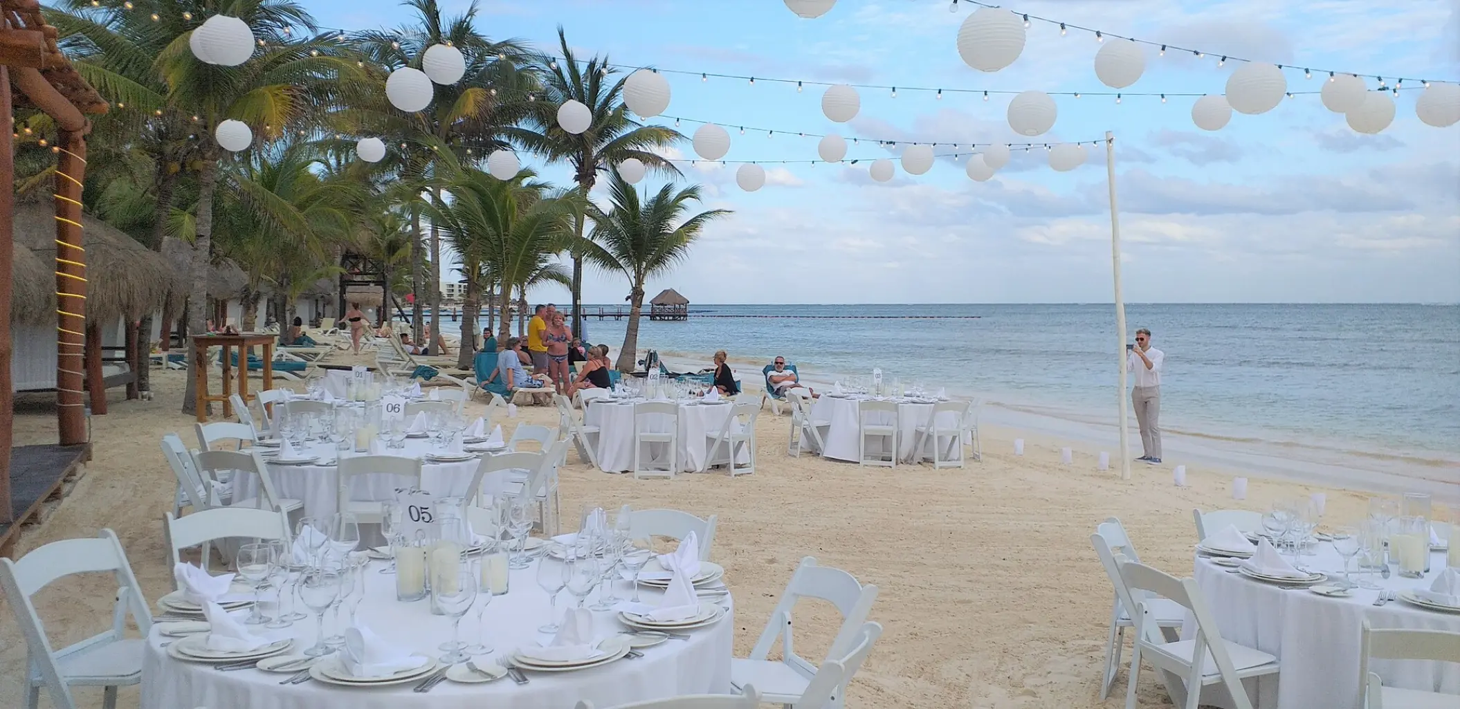 Beachfront wedding reception with white lanterns and round tables at Azul Beach Resort, Negril