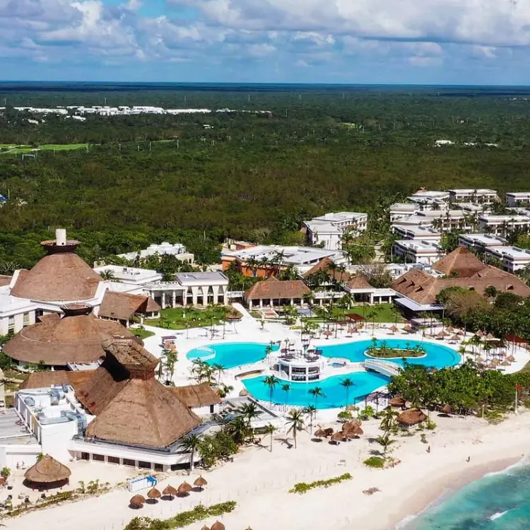 Aerial view of Bahia Principe Grand Tulum pools and beachfront buildings surrounded by lush jungle, Tulum