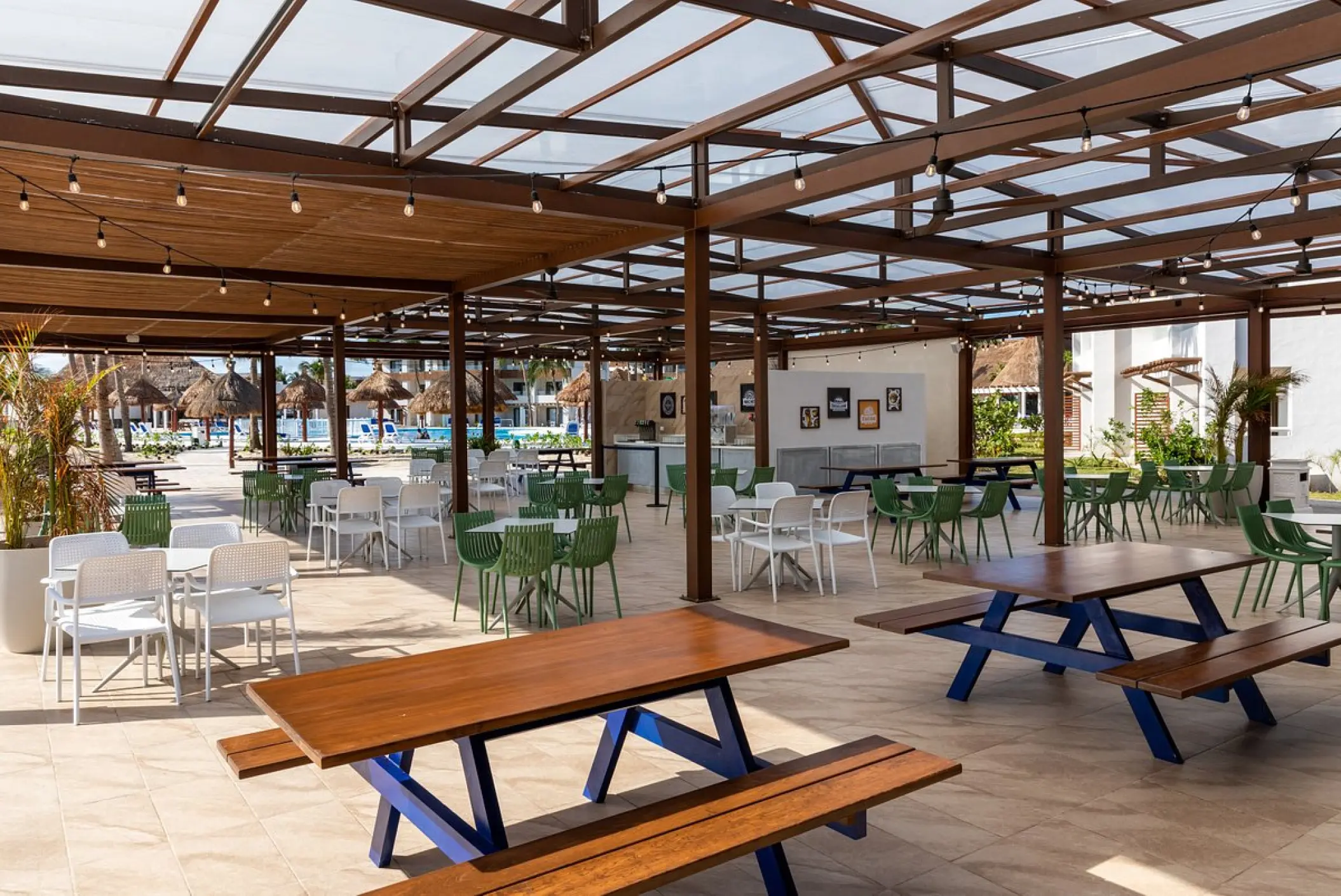 Outdoor terrace restaurant with picnic tables and string lights at Bahia Principe Grand Tulum
