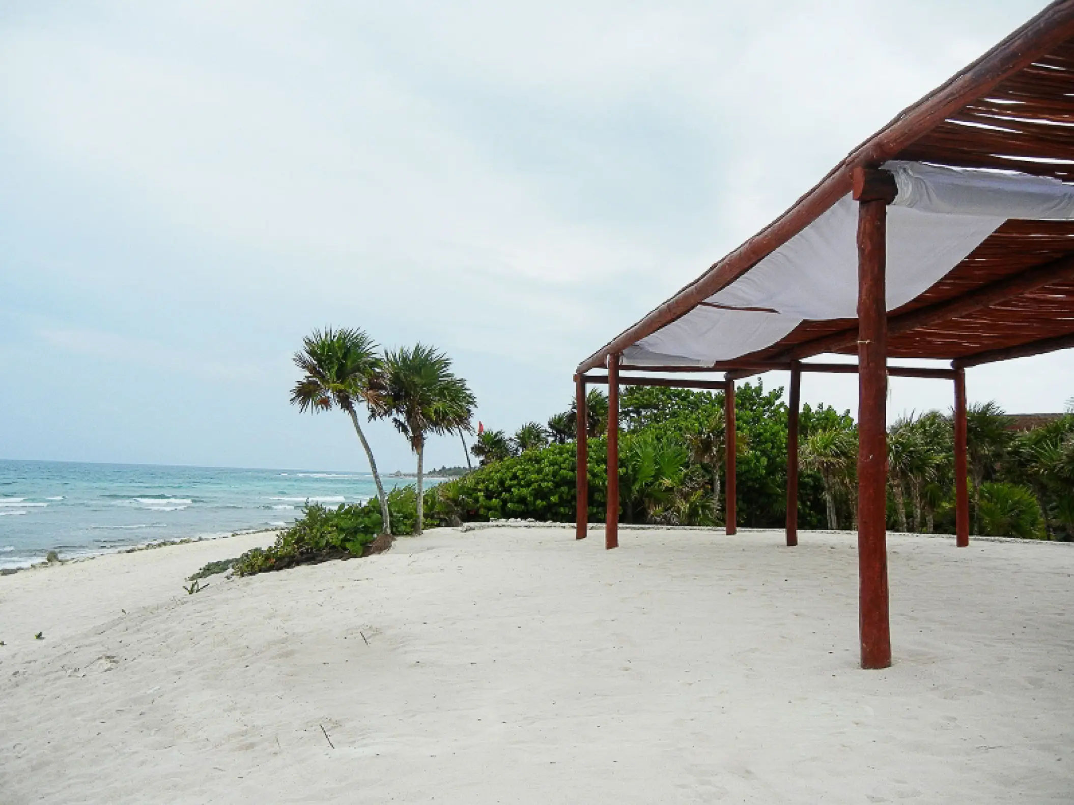 Wooden beachfront pergola on white sand at Bahia Principe Grand Tulum