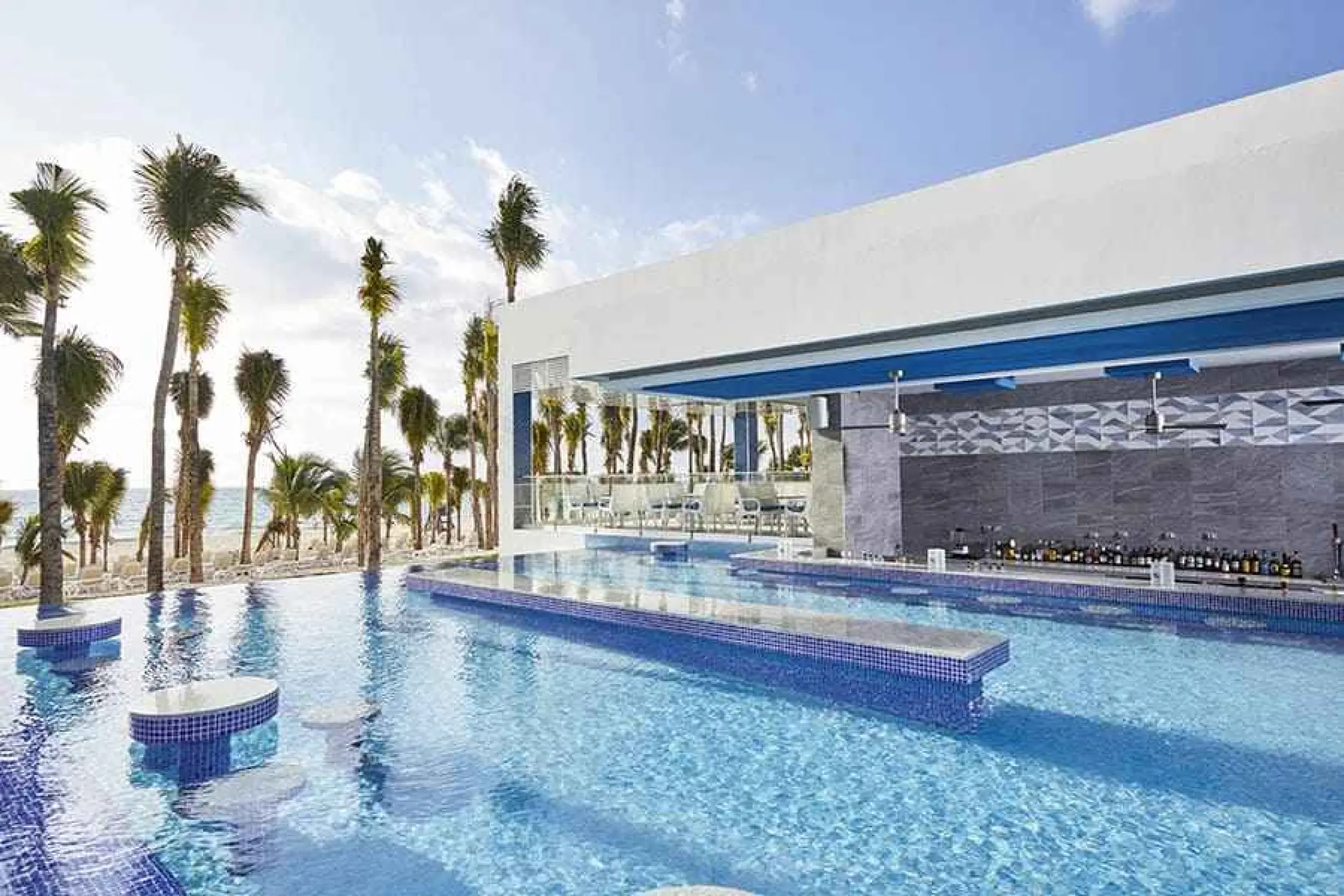 Swim-up bar and infinity pool surrounded by palm trees at Riu Palace Riviera Maya, Playa Del Carmen