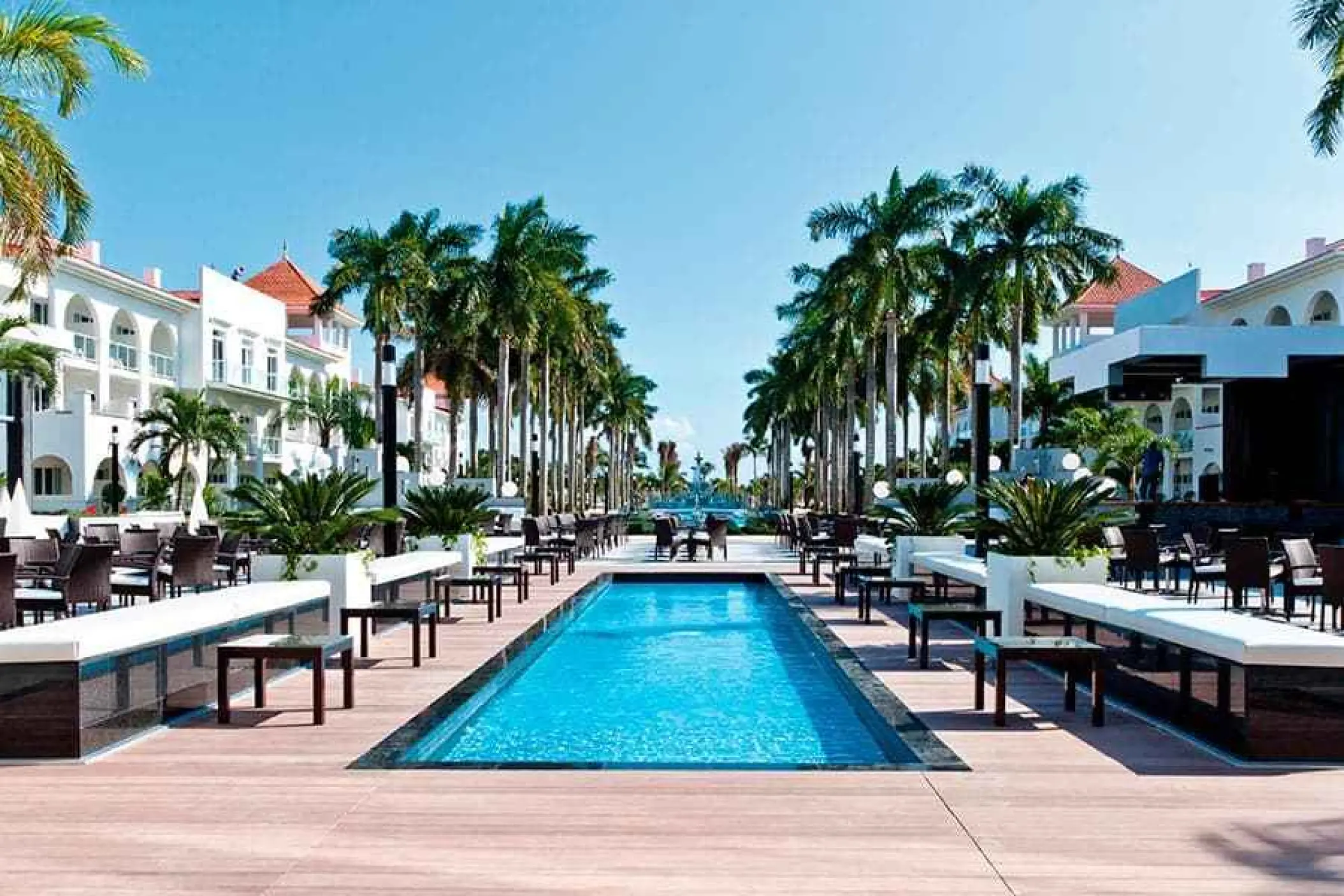 Riu Palace Mexico courtyard pool and outdoor lounge area lined with palm trees, Playa Del Carmen