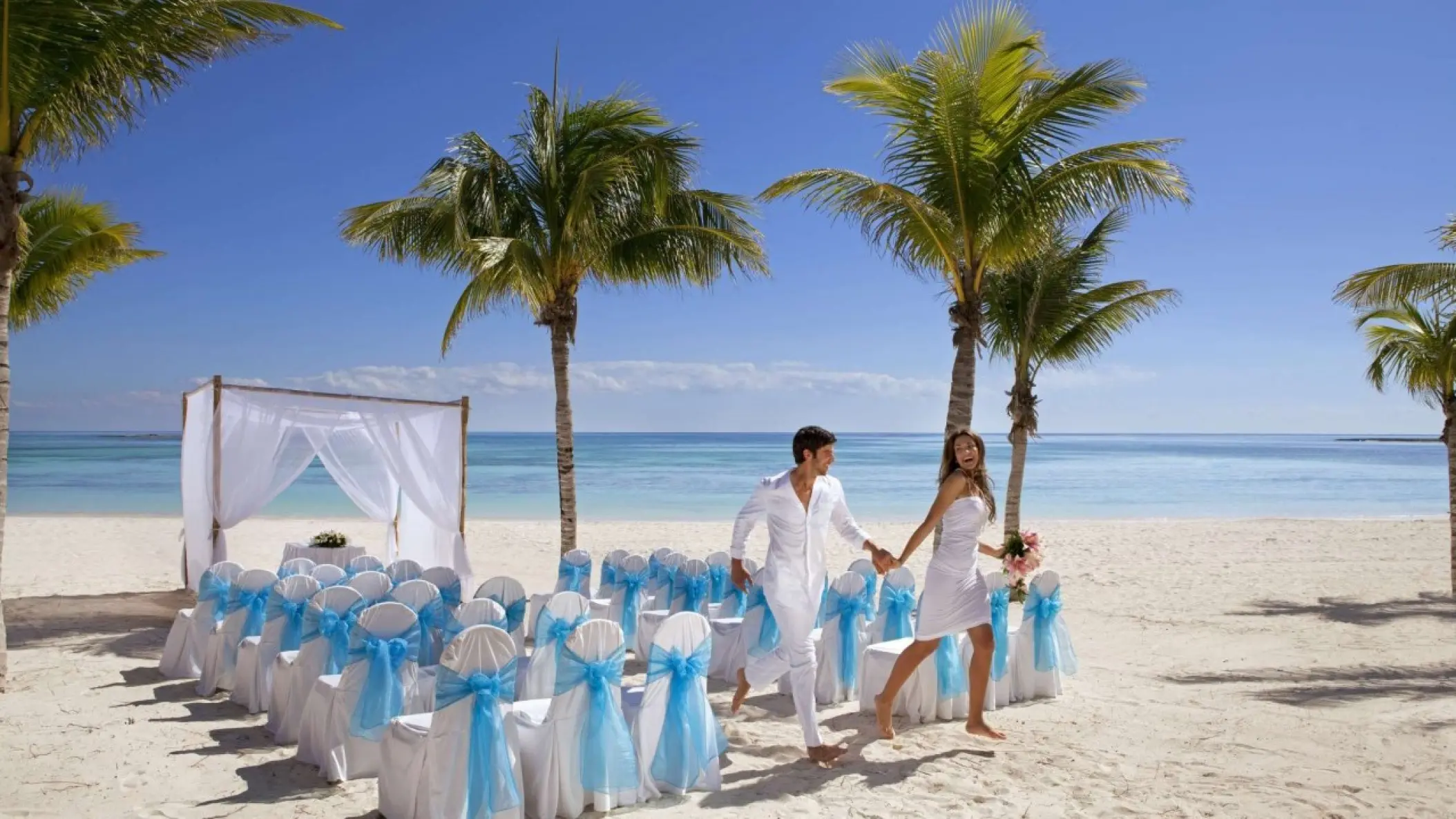 Couple running through a beach ceremony setup at Barcelo Maya Riviera, Riviera Maya
