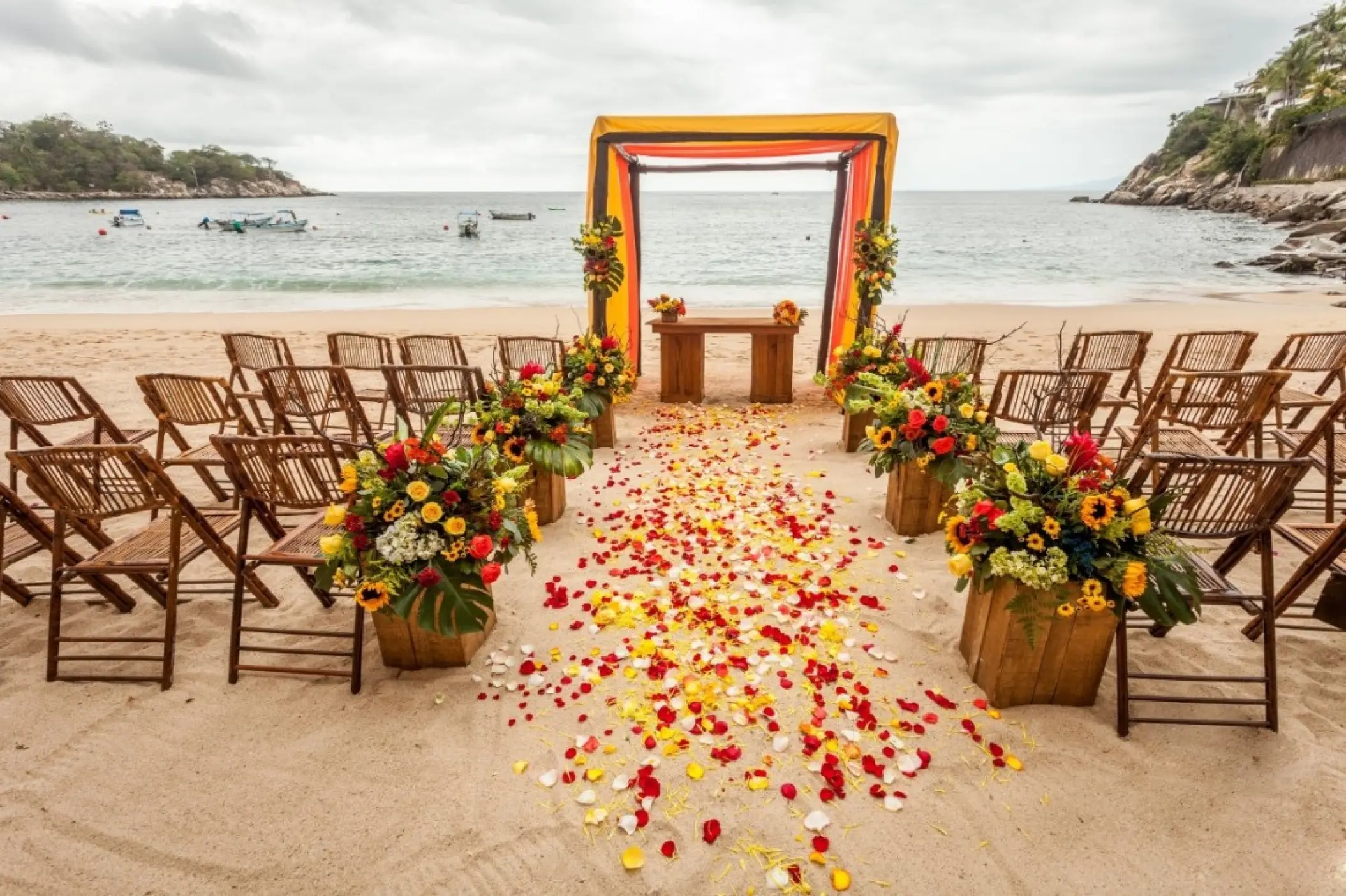 Beachfront wedding ceremony with an orange hued arch and petal aisle at Barcelo Maya Beach, Riviera Maya